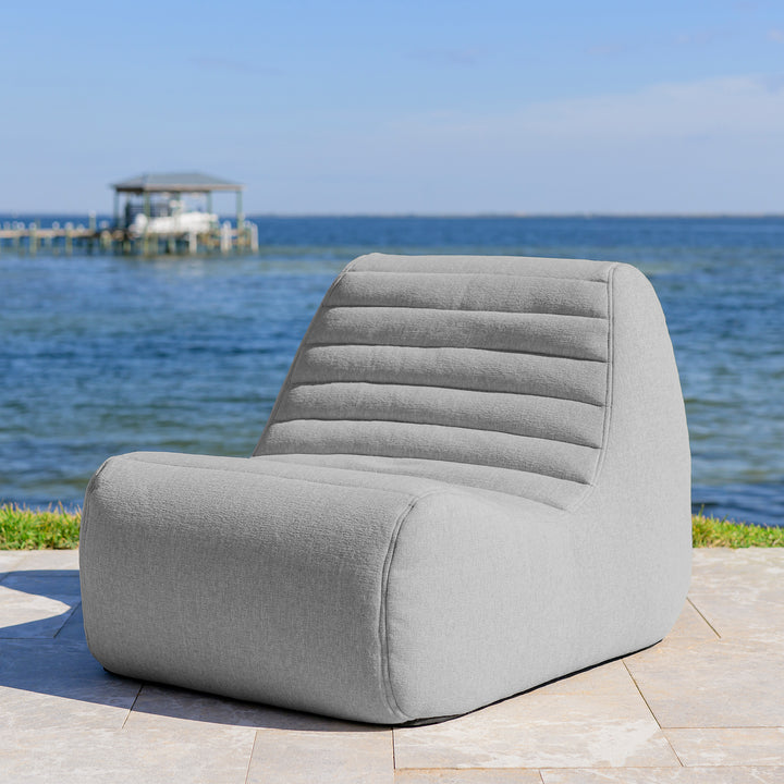 Gray chair on a patio with a scenic view of water and dock in the background #color_port-gray-outdoor-performance-linen