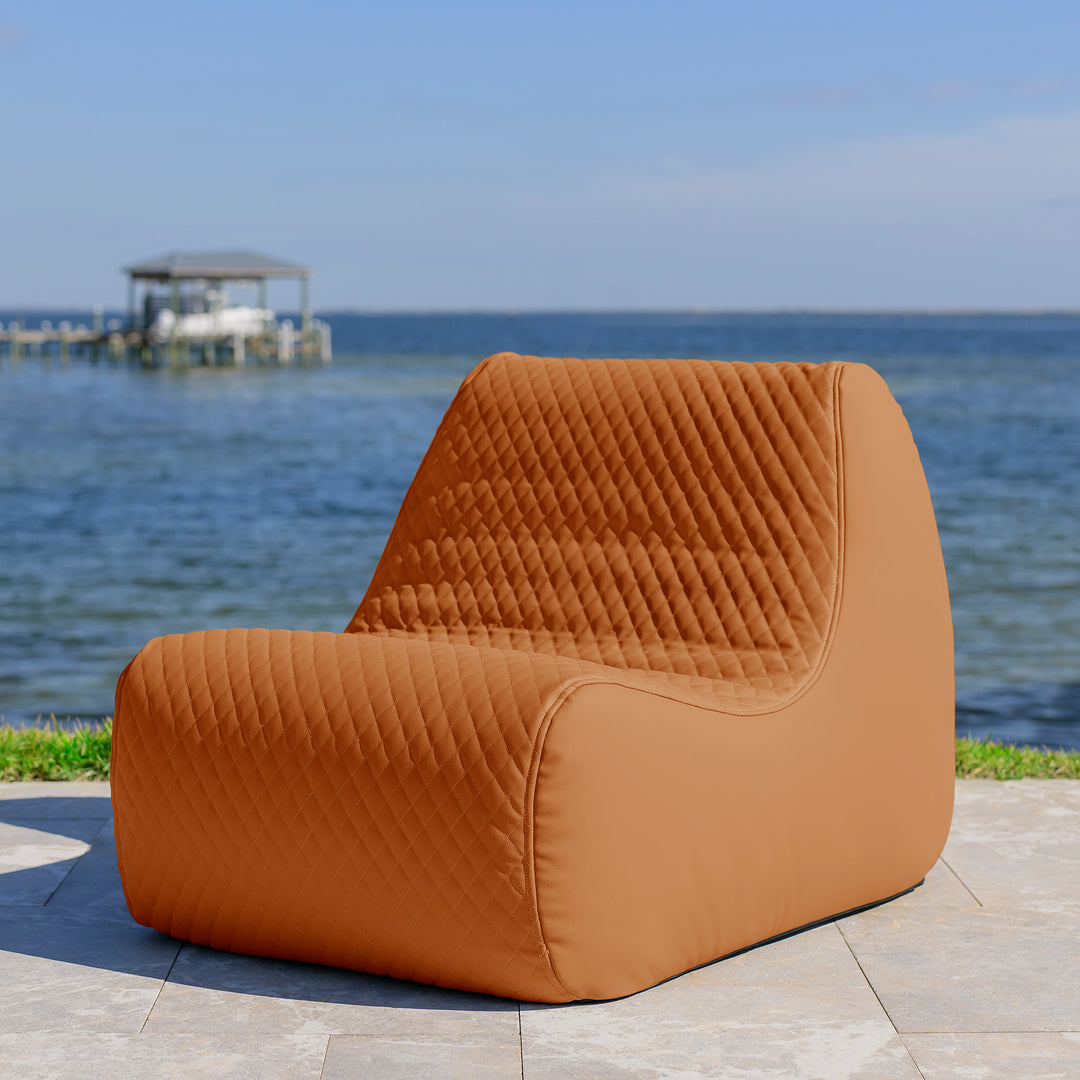 Brown quilted chair by the sea with a clear blue sky #color_honey-sand-outdoor-vegan-leather