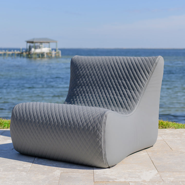Gray quilted chair on a patio with a waterfront background #color_moonlit-gray-outdoor-vegan-leather