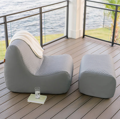 Gray outdoor chair and ottoman on a wooden deck with water view 