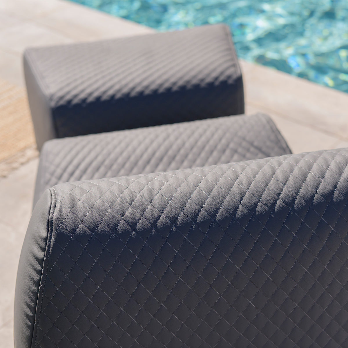 Gray quilted cushions on a chair by a pool 