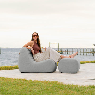 Woman sitting on a gray outdoor chair by a waterfront. 