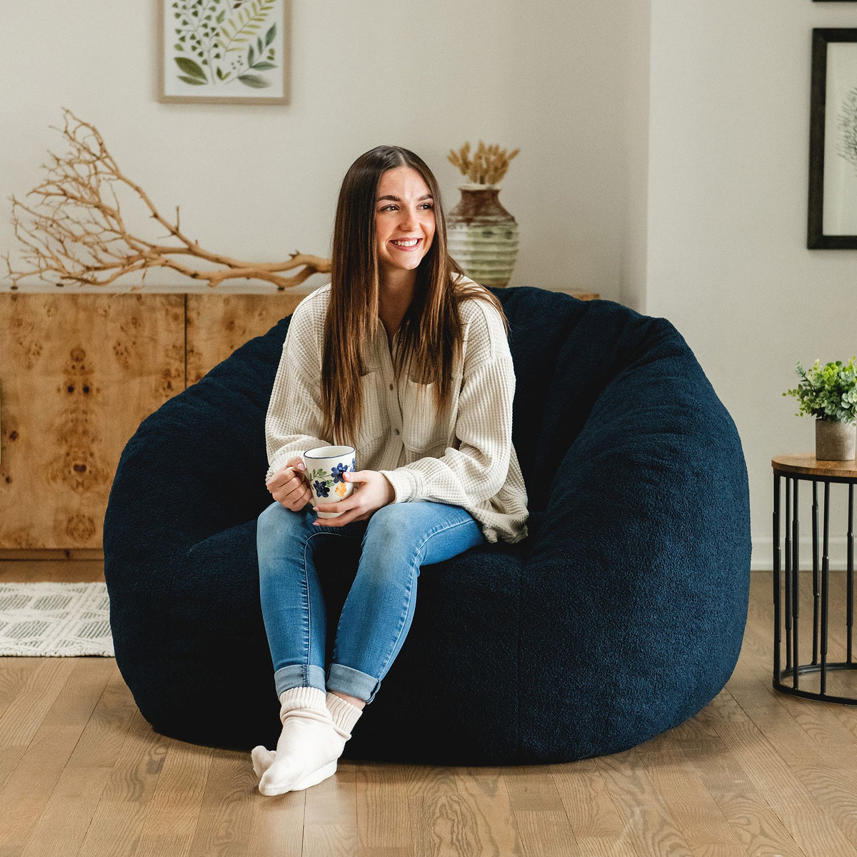 Woman sitting in a blue cloud-like chair in the living room 