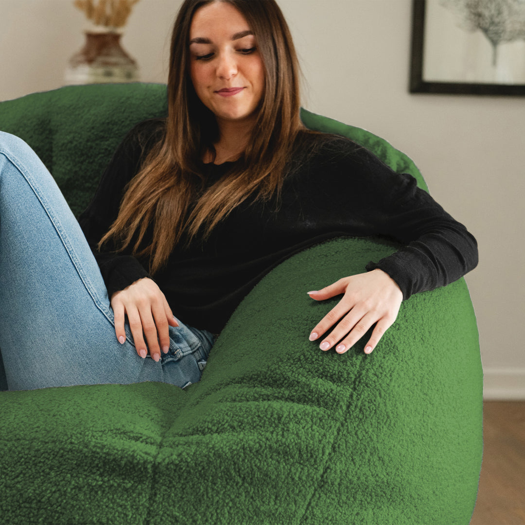 Woman sitting on a green bean bag chair in a room with a neutral color scheme. 