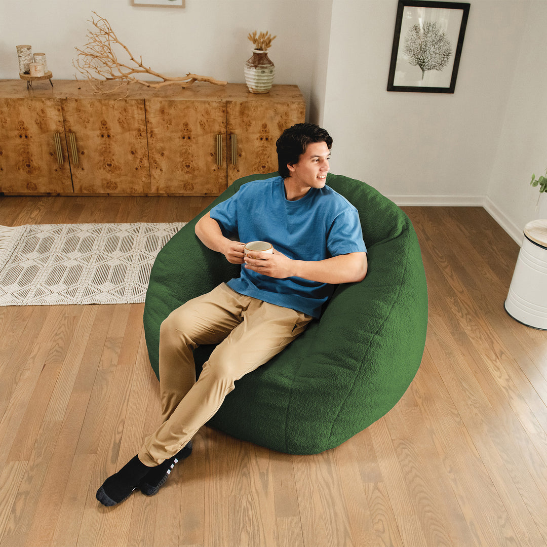 Man sitting on a green bean bag chair in a living room. 