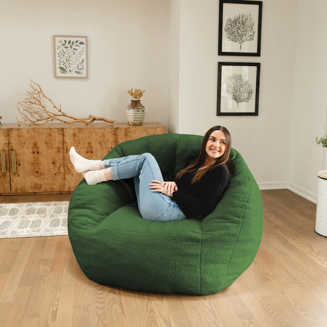 Woman sitting in a green bean bag chair in a room with wooden floor and wall decorations. 