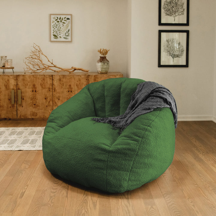 Green bean bag chair with a blanket in a room with wooden floor and wall decorations. 