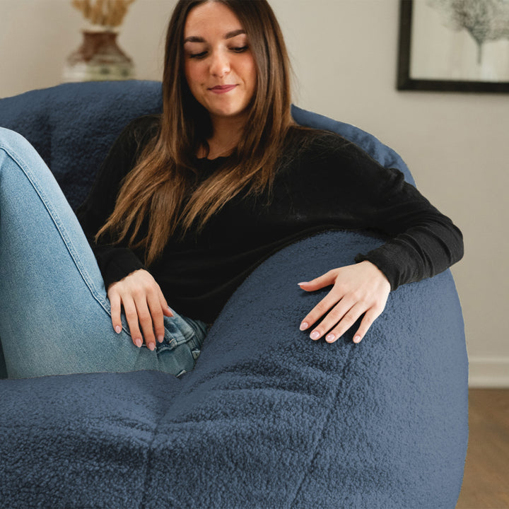 Woman sitting on a large blue bean bag chair in a room with a neutral color scheme. 