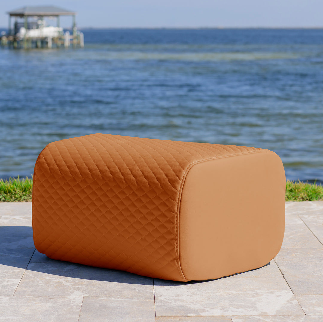 Brown quilted ottoman on a patio with ocean view #color_honey-sand-outdoor-vegan-leather