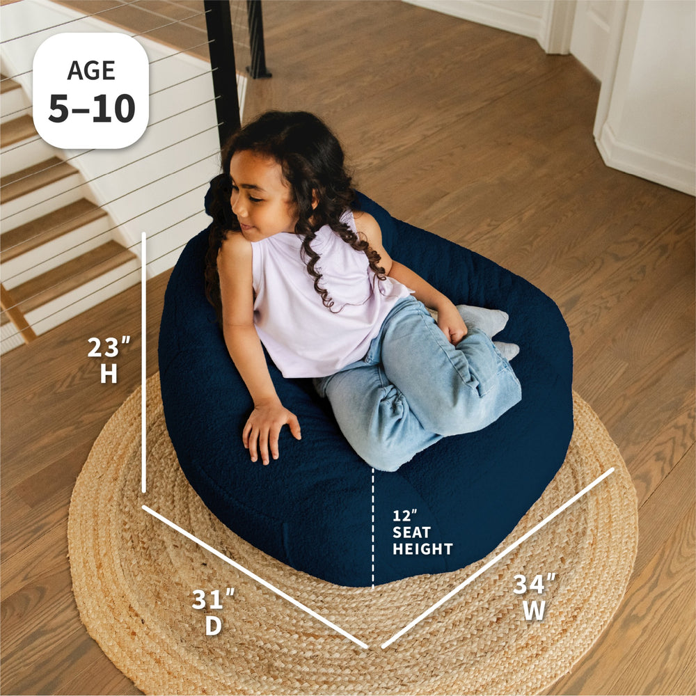 Child sitting on a navy bean bag chair with measurements displayed #color_deep-blue-teddy-boucle