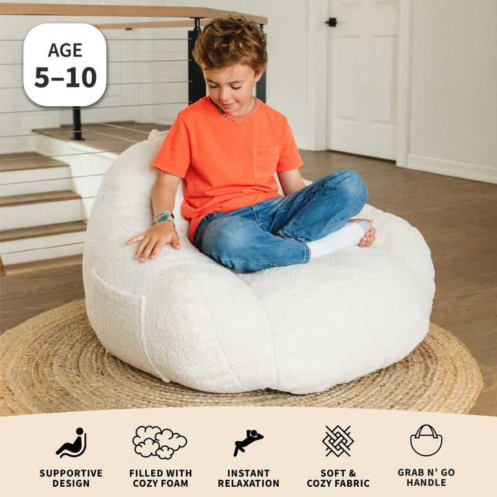 Child sitting on a white bean bag chair in a home setting with product features displayed below. #color_icing-teddy-boucle