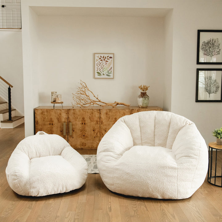 Two white bean bag chairs, kids and adult sizes, in a living room setting with wooden furniture and decor. #color_icing-teddy-boucle