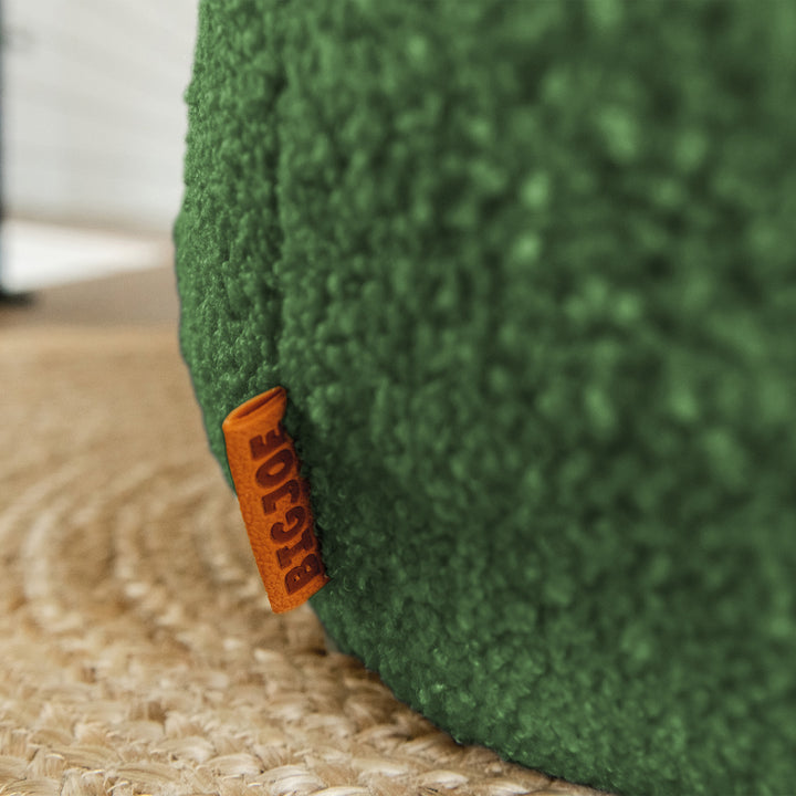 Close-up of a green textured product with an orange label on a carpeted floor. 