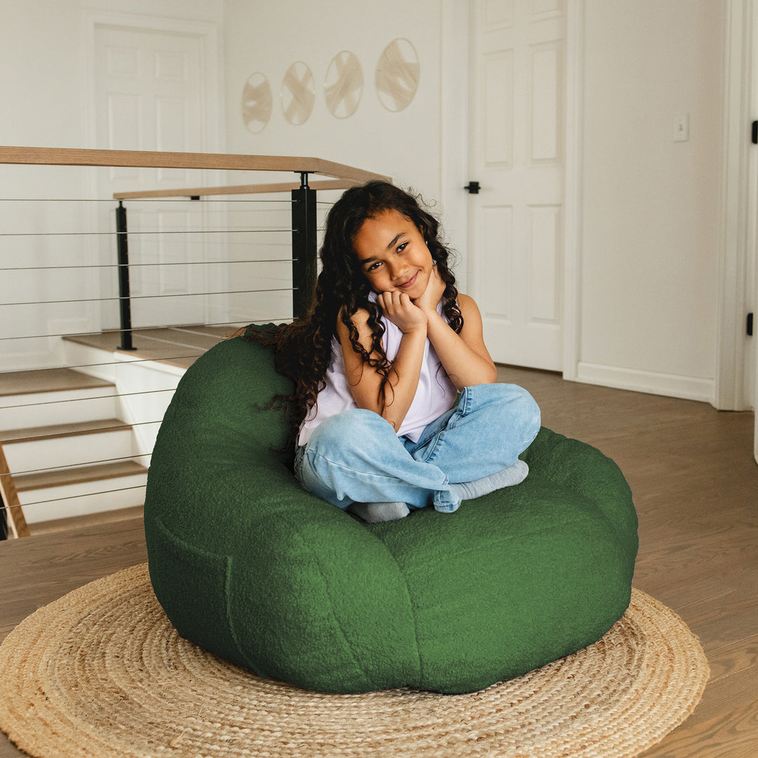 Young girl sitting on a green bean bag chair in a home setting. 