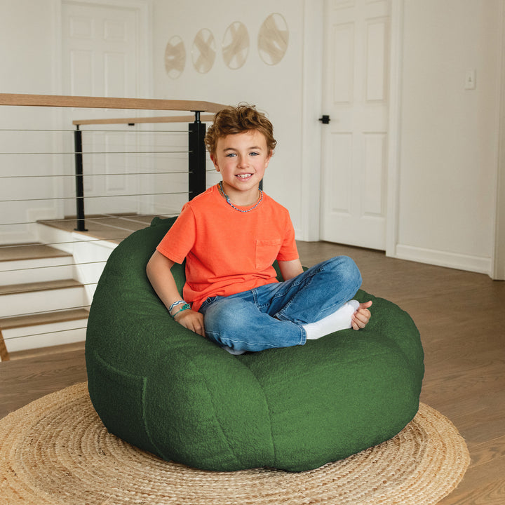 Child sitting on a green bean bag chair in a home setting 