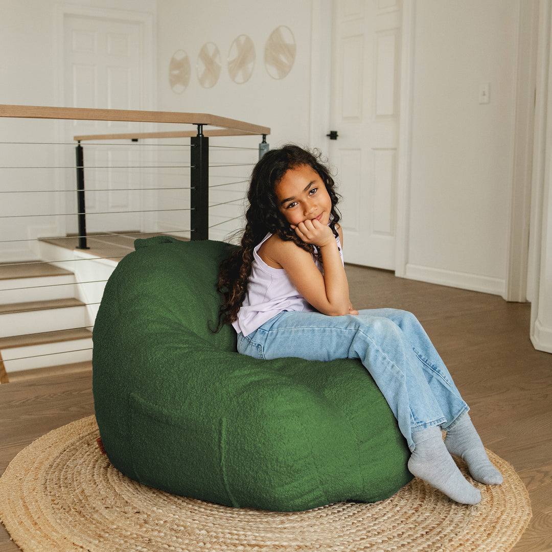 Child sitting on a green bean bag chair in a home setting 