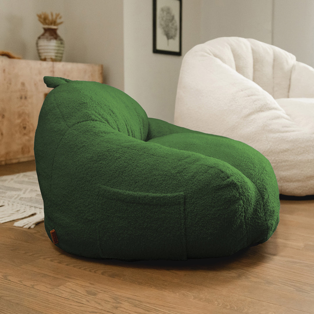 Green bean bag chair in a room with a white chair and decorative items. 