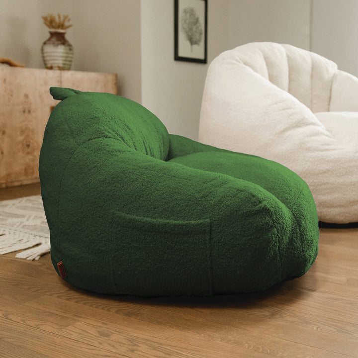 Green bean bag chair in a room with a white chair and decorative items. 