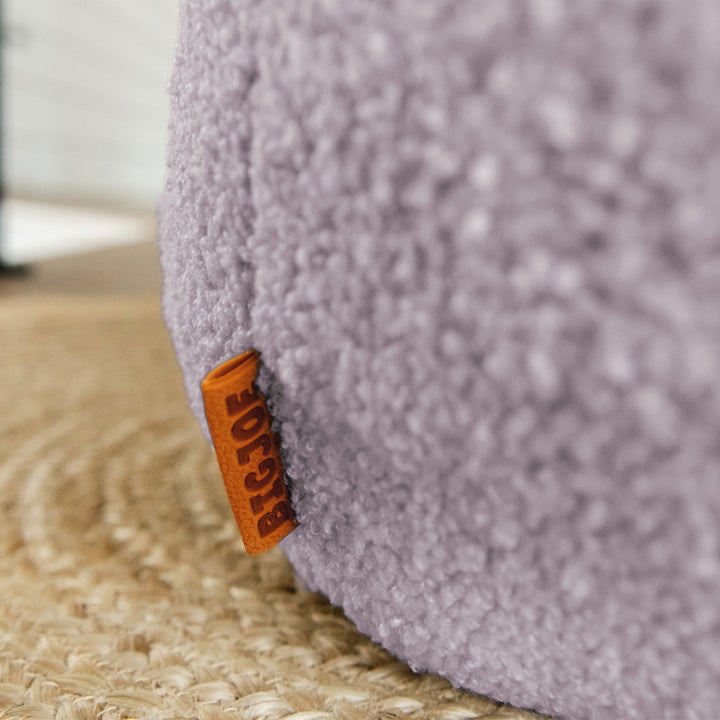 Close-up of a textured purple product with an orange tag on a carpeted floor. 