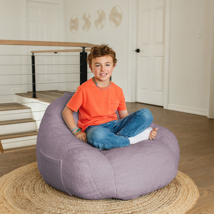 Child sitting on a purple bean bag chair in a home setting 