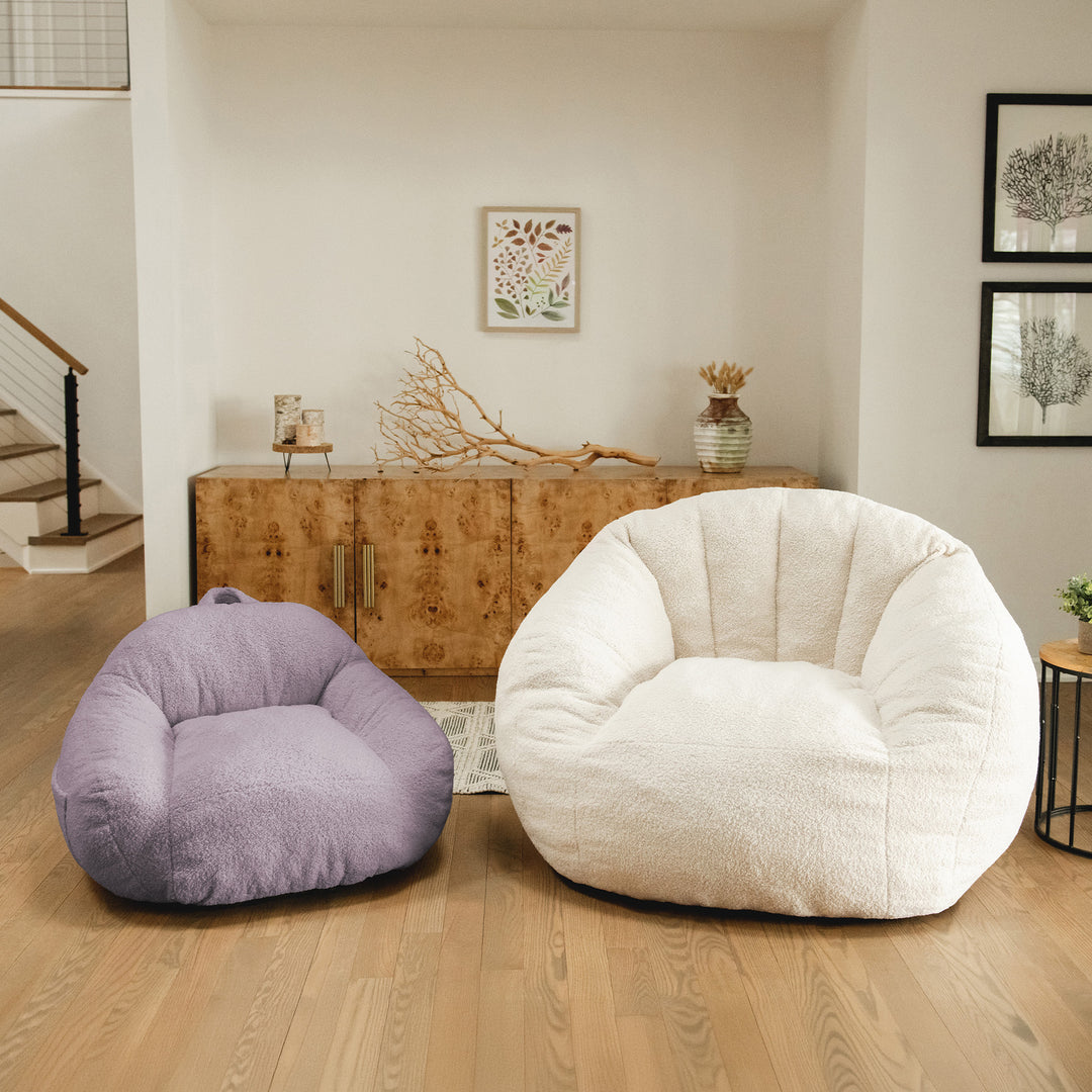 Two bean bags, one purple and one white, in a living room setting with a wooden cabinet and decor. 