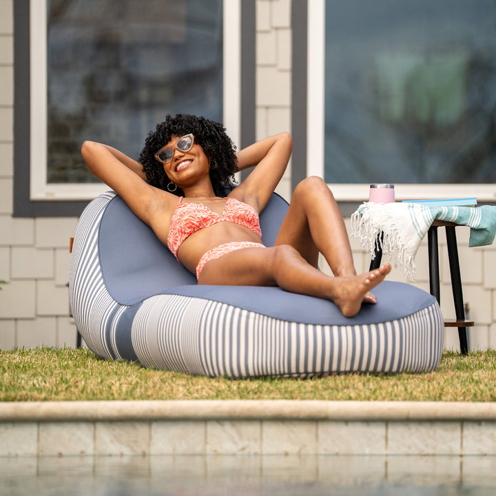 Woman relaxing on a striped bean bag by a poolside #color_weekend-navy-stripe-olefin