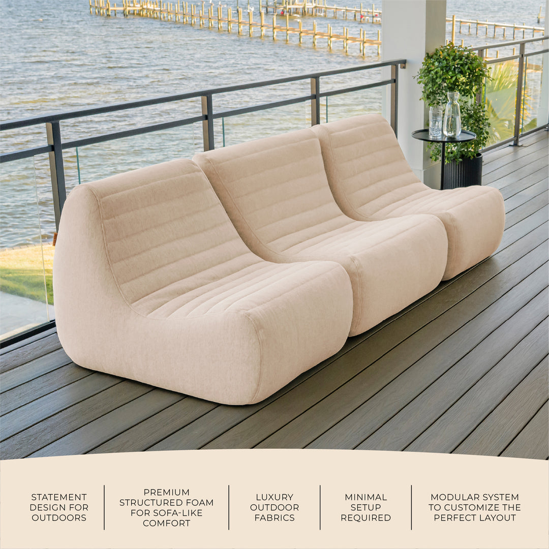 Beige sofa on a wooden deck by a waterfront with text highlighting features. #color_sunlit-cream-outdoor-performance-linen