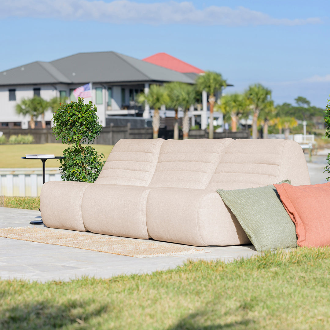 Beige outdoor sofa with colorful cushions on a patio with a scenic background #color_sunlit-cream-outdoor-performance-linen