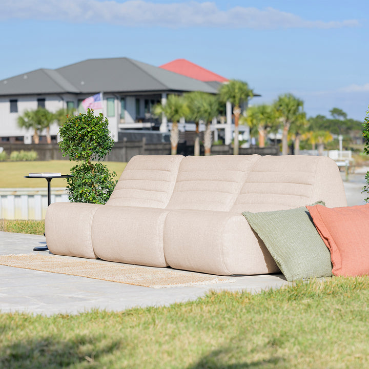 Beige outdoor sofa with colorful cushions on a patio with a scenic background #color_sunlit-cream-outdoor-performance-linen