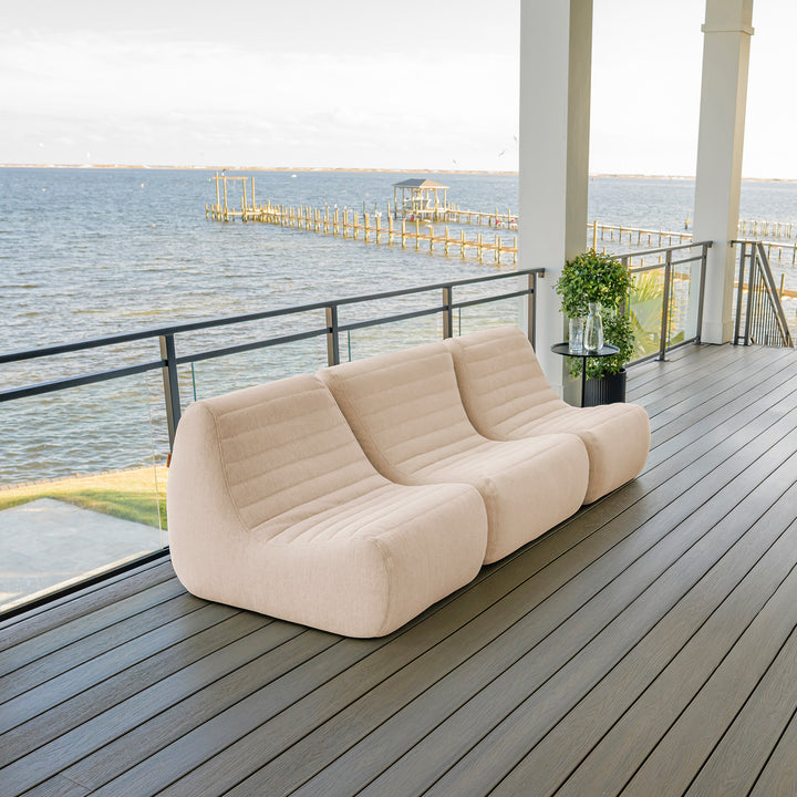 Beige outdoor sofa on a wooden deck with ocean view #color_sunlit-cream-outdoor-performance-linen