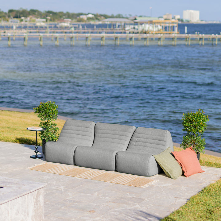 Gray outdoor sofa with colorful cushions on a patio by a waterfront. #color_port-gray-outdoor-performance-linen