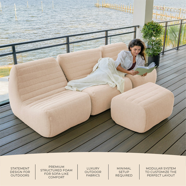Woman relaxing on an inflatable outdoor sofa by a waterfront. #color_sunlit-cream-outdoor-performance-linen