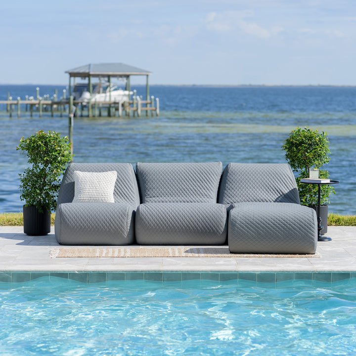 Gray outdoor sofa by a pool with a scenic background of water and sky. #color_moonlit-gray-outdoor-vegan-leather