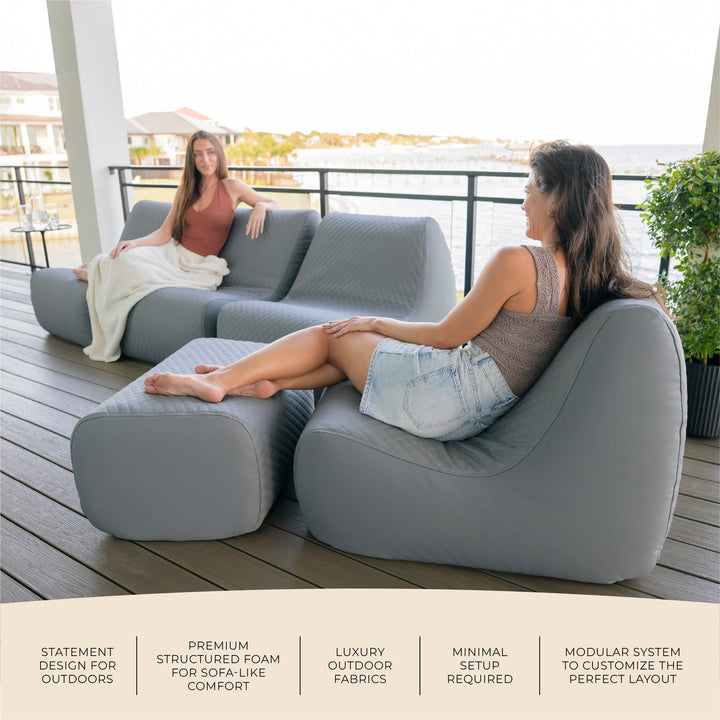 Two women sitting on a modern outdoor sofa set on a deck with scenic background #color_moonlit-gray-outdoor-vegan-leather