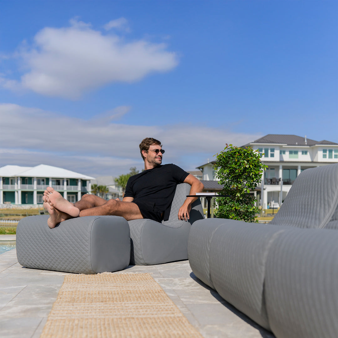 Man sitting on a modern outdoor sofa with a scenic background #color_moonlit-gray-outdoor-vegan-leather