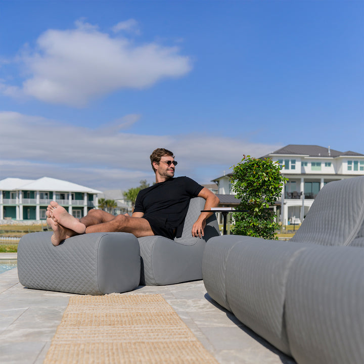 Man sitting on a modern outdoor sofa with a scenic background #color_moonlit-gray-outdoor-vegan-leather