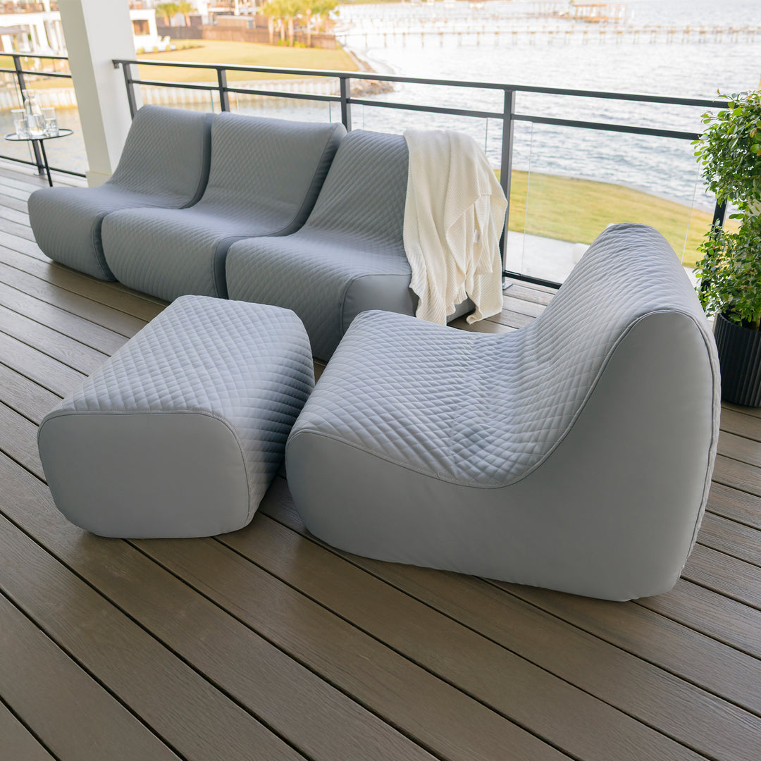 Modern outdoor furniture set on a wooden deck with a view of water and greenery. #color_moonlit-gray-outdoor-vegan-leather