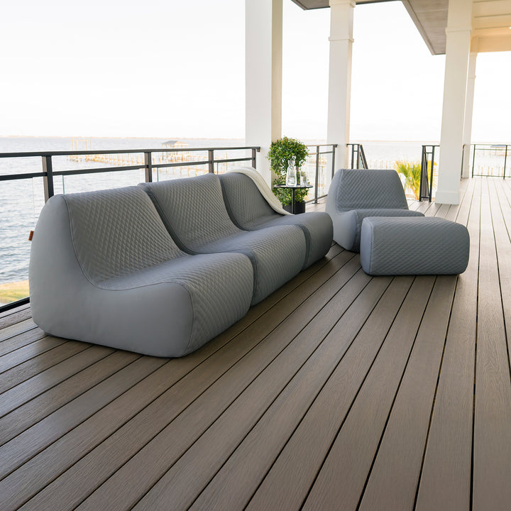 Modern outdoor sofa set on a wooden deck with a waterfront view. #color_moonlit-gray-outdoor-vegan-leather