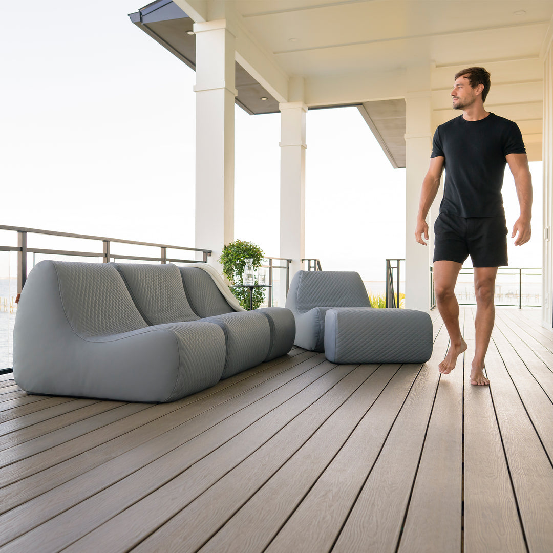 Man standing on a wooden deck with modern outdoor furniture #color_moonlit-gray-outdoor-vegan-leather