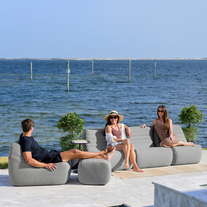 People relaxing on outdoor furniture by a body of water #color_port-gray-outdoor-performance-linen