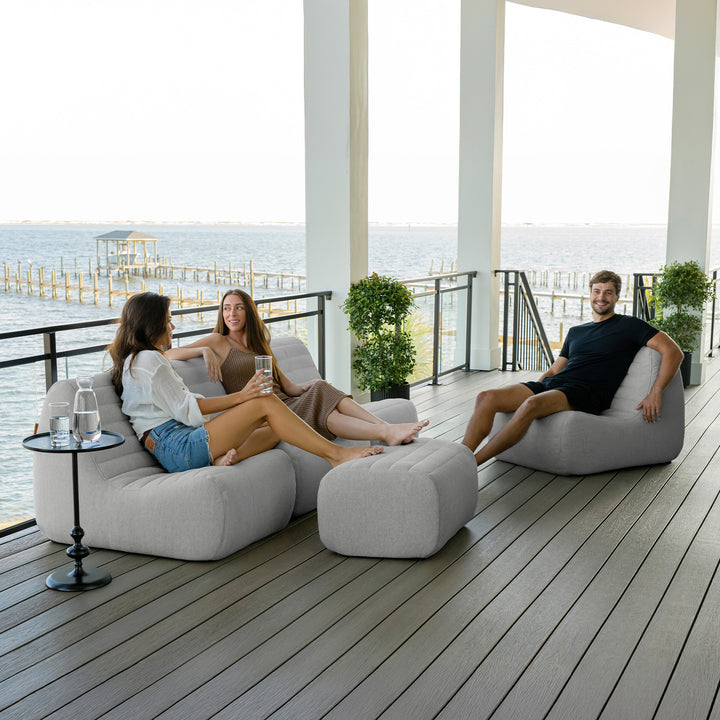 People relaxing on modern outdoor furniture with a waterfront view. #color_port-gray-outdoor-performance-linen