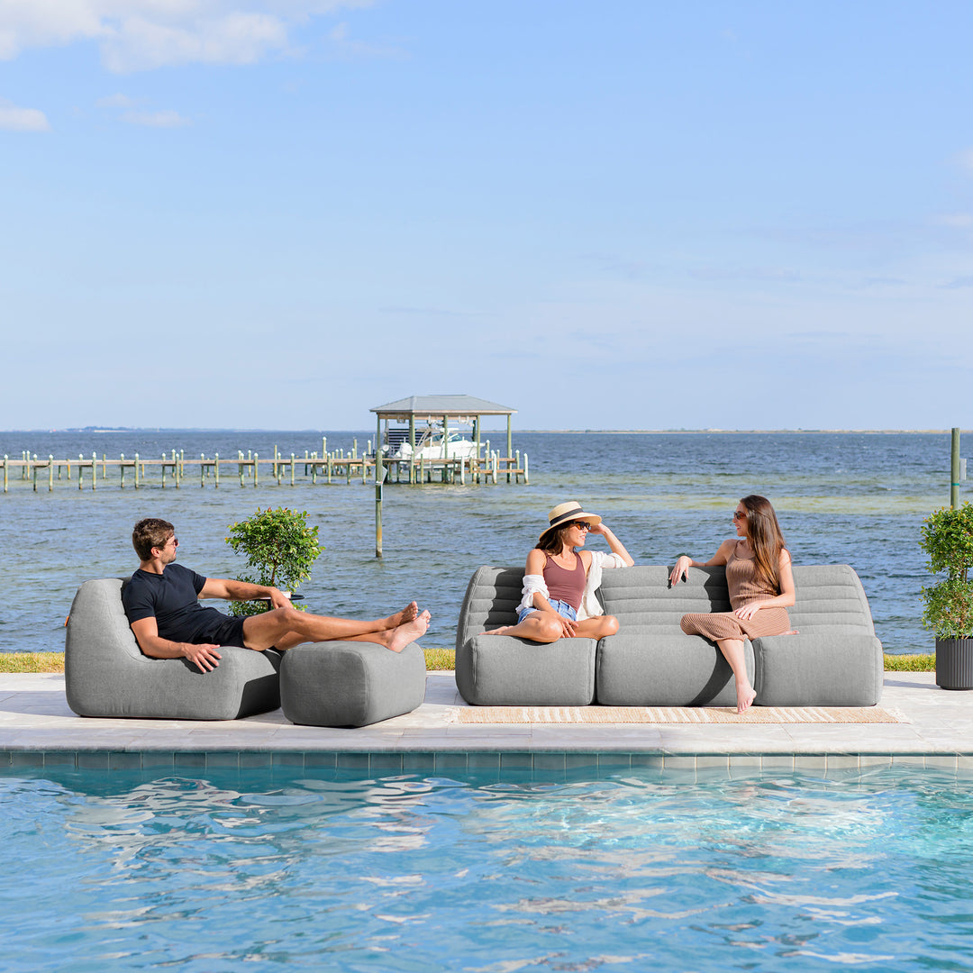 People relaxing on outdoor sofa by a pool with a scenic background #color_port-gray-outdoor-performance-linen