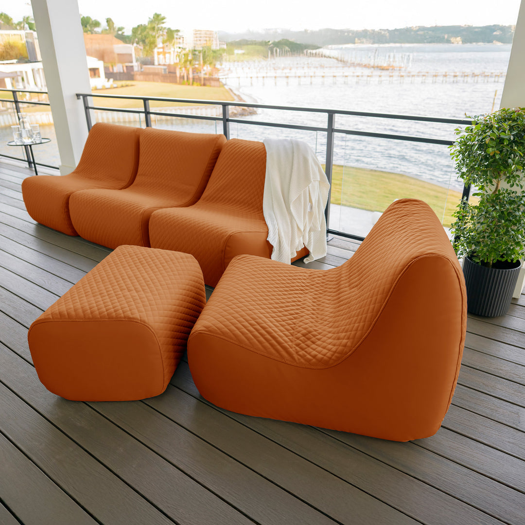 Orange outdoor sofa set on a wooden deck with a waterfront view. #color_honey-sand-outdoor-vegan-leather