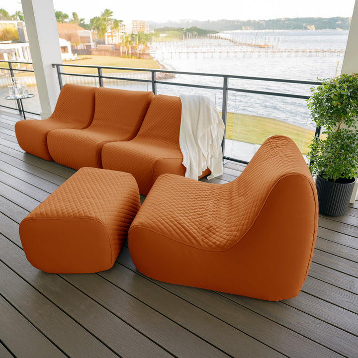 Orange outdoor sofa set on a wooden deck with a waterfront view. #color_honey-sand-outdoor-vegan-leather