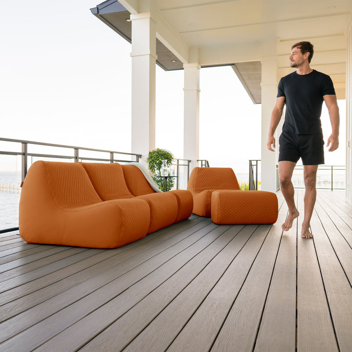 Man walking on a wooden deck with orange outdoor furniture #color_honey-sand-outdoor-vegan-leather