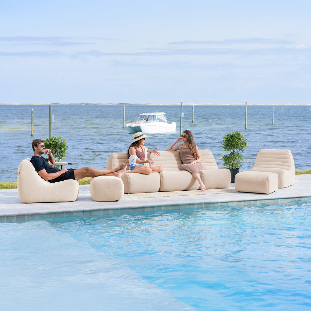 People relaxing on a modern outdoor sofa by a pool with a scenic ocean view.  #color_sunlit-cream-outdoor-performance-linen