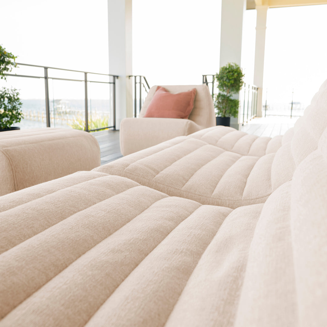 Beige sofa with a pink pillow in a modern living room #color_sunlit-cream-outdoor-performance-linen