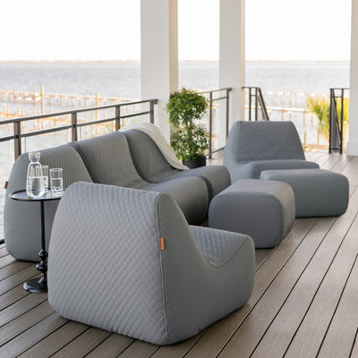 Gray outdoor furniture set on a wooden deck with a waterfront view. 