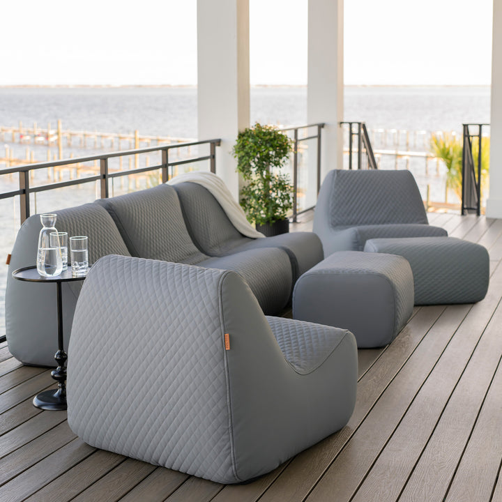 Gray outdoor furniture set on a wooden deck with a waterfront view. #color_moonlit-gray-outdoor-vegan-leather