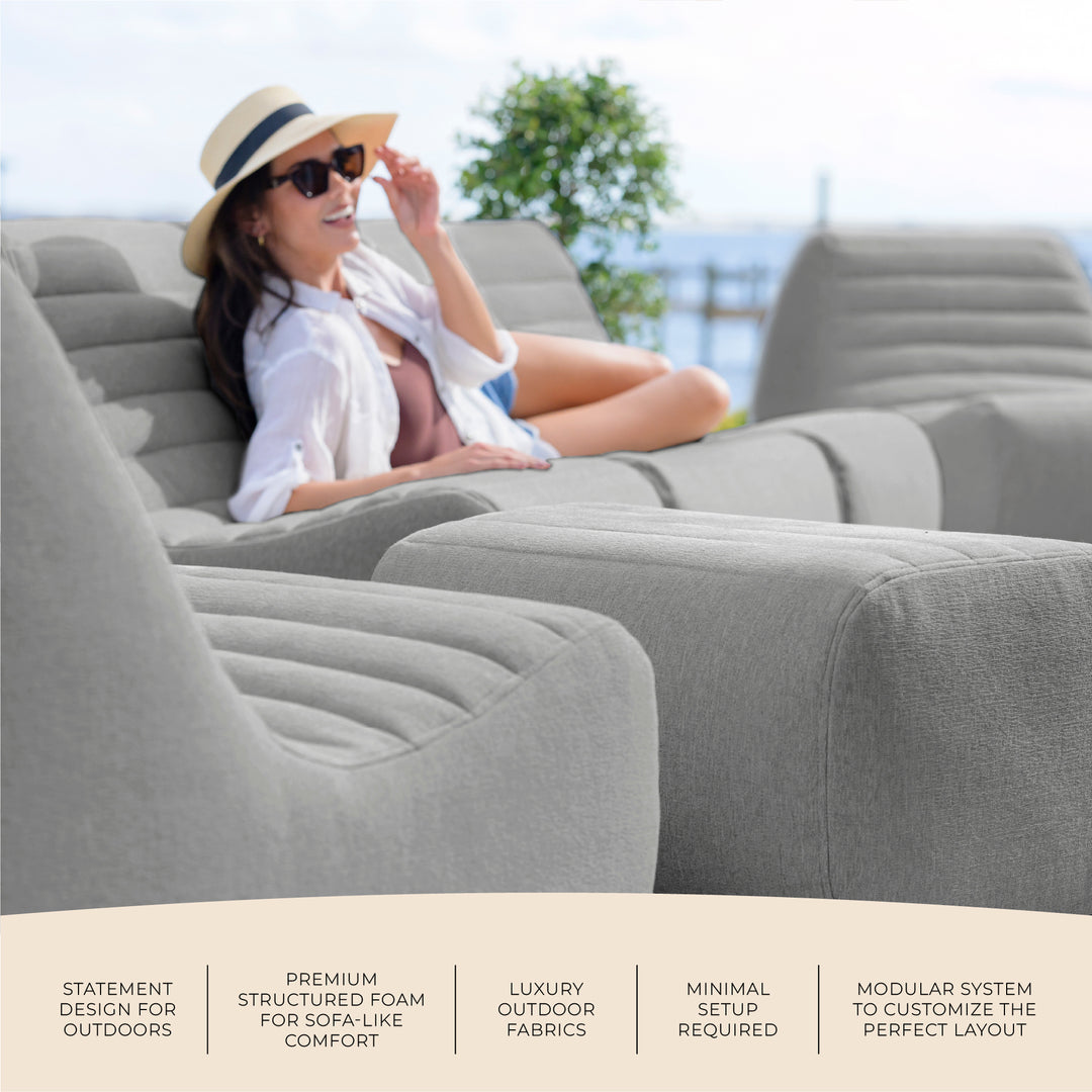 Woman relaxing on a gray inflatable outdoor sofa with text highlighting features. #color_port-gray-outdoor-performance-linen
